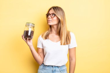 Profil görünümündeki güzel sarışın kız hayal mi kuruyor, hayal mi kuruyor yoksa hayal mi kuruyor? kahve çekirdeği konsepti