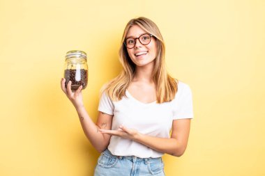 Güzel sarışın kız neşeyle gülümsüyor, mutlu hissediyor ve bir konsept gösteriyor. kahve çekirdeği konsepti