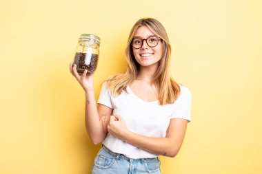 Güzel sarışın kız kendini mutlu hissediyor ve bir meydan okumayla yüzleşiyor ya da kutluyor. kahve çekirdeği konsepti