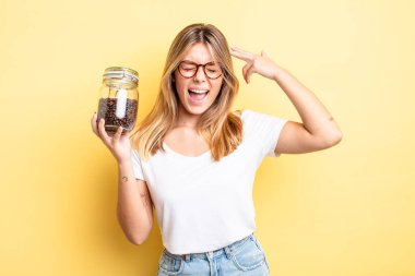 Güzel sarışın kız mutsuz ve stresli görünüyor, intihar jesti silah işareti yapıyor. kahve çekirdeği konsepti