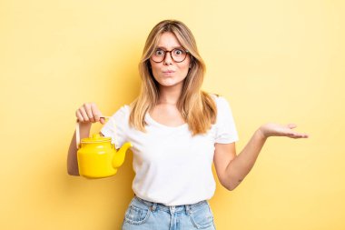 Güzel sarışın kız şaşkın, şaşkın ve şüpheci hissediyor. çaydanlık konsepti