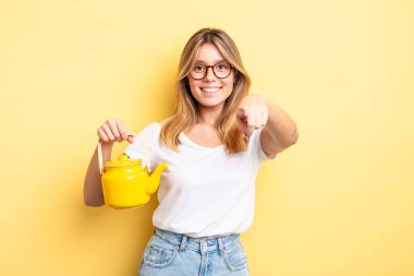 Güzel sarışın kız seni seçen kamerayı işaret ediyor. çaydanlık konsepti