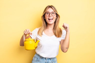 Güzel sarışın kız şokta, gülüyor ve başarıyı kutluyor. çaydanlık konsepti