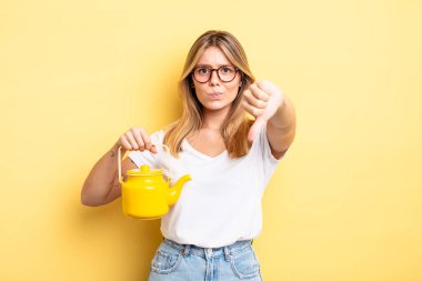 Güzel sarışın kız kendini kötü hissediyor, baş parmağını kaldırıyor. çaydanlık konsepti