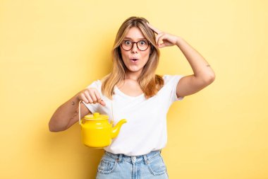 Güzel sarışın kız mutlu, şaşkın ve şaşırmış görünüyor. çaydanlık konsepti