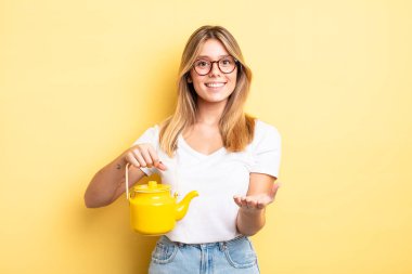 Güzel sarışın kız mutlu bir şekilde gülümsüyor ve bir konsept sunuyor. çaydanlık konsepti