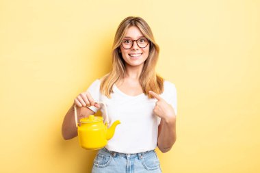 Güzel sarışın kız mutlu hissediyor ve heyecanla kendini işaret ediyor. çaydanlık konsepti