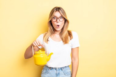 Güzel sarışın kız çok şaşırmış ya da şaşkın görünüyor. çaydanlık konsepti