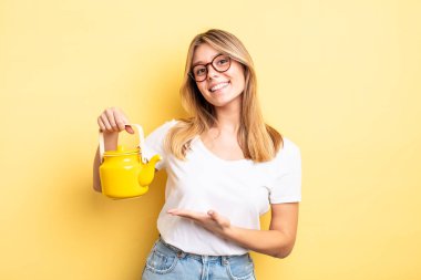 Güzel sarışın kız neşeyle gülümsüyor, mutlu hissediyor ve bir konsept gösteriyor. çaydanlık konsepti