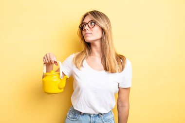 Profil görünümündeki güzel sarışın kız hayal mi kuruyor, hayal mi kuruyor yoksa hayal mi kuruyor? çaydanlık konsepti