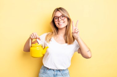 Güzel sarışın kız gülümsüyor ve arkadaş canlısı görünüyor. İki numarayı gösteriyor. çaydanlık konsepti