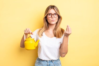 Güzel sarışın kız kapiş ya da para hareketi yapıyor, sana ödemeni söylüyor. çaydanlık konsepti