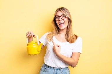 Güzel sarışın kız heyecanlı ve şaşırmış görünüyor. çaydanlık konsepti