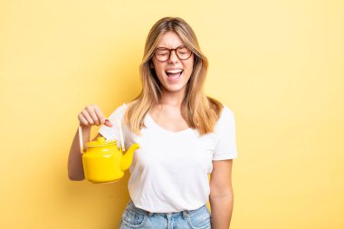 Güzel sarışın kız agresif bir şekilde bağırıyor, çok kızgın görünüyor. çaydanlık konsepti