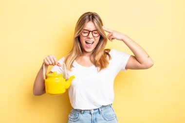 Güzel sarışın kız mutsuz ve stresli görünüyor, intihar jesti silah işareti yapıyor. çaydanlık konsepti