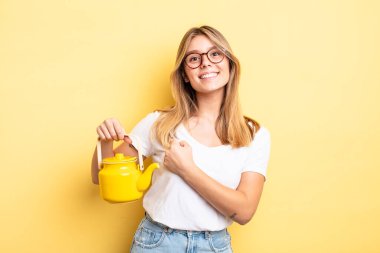 Güzel sarışın kız kendini mutlu hissediyor ve bir meydan okumayla yüzleşiyor ya da kutluyor. çaydanlık konsepti