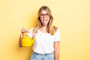 Güzel sarışın kız iğreniyor, sinirleniyor ve dilini çıkarıyor. çaydanlık konsepti