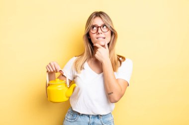 Güzel sarışın kız düşünüyor, kuşkulu ve şaşkın hissediyor. çaydanlık konsepti