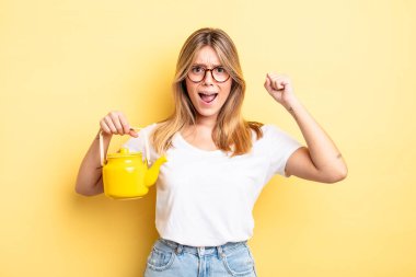 Güzel sarışın kız sinirli bir ifadeyle agresif bir şekilde bağırıyor. çaydanlık konsepti