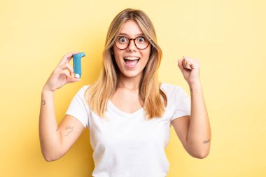 Güzel sarışın kız şokta, gülüyor ve başarıyı kutluyor. astım spreyi kavramı