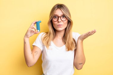 Güzel sarışın kız şaşkın, şaşkın ve şüpheci hissediyor. astım spreyi kavramı