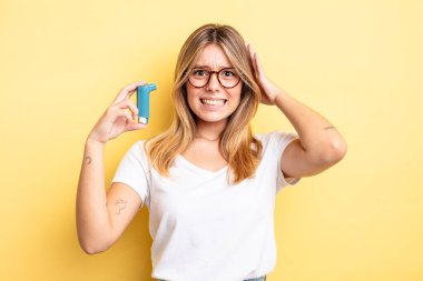 Güzel sarışın kız stresli, endişeli ya da korkmuş, elleri başının üstünde. astım spreyi kavramı