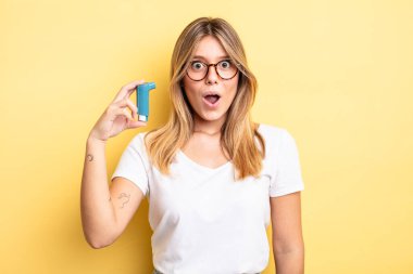 Güzel sarışın kız çok şaşırmış ya da şaşkın görünüyor. astım spreyi kavramı