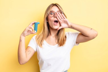 Güzel sarışın kız kendini mutlu hissediyor, elleri ağzının kenarında bağırıyor. astım spreyi kavramı