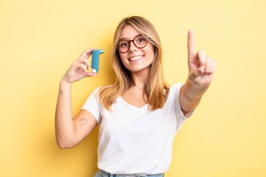 Güzel sarışın kız gururla gülümsüyor ve kendinden emin bir numara oluyor. astım spreyi kavramı