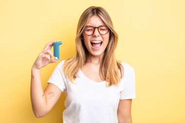 Güzel sarışın kız agresif bir şekilde bağırıyor, çok kızgın görünüyor. astım spreyi kavramı