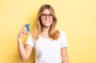 Güzel sarışın kız şaşkın ve şaşkın görünüyor. astım spreyi kavramı