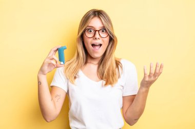Güzel sarışın kız kendini mutlu hissediyor, bir çözüm ya da fikir bulduğuna şaşırıyor. astım spreyi kavramı