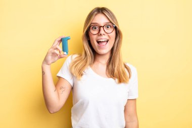 Güzel sarışın kız mutlu ve hoş bir şekilde şaşırmış görünüyor. astım spreyi kavramı