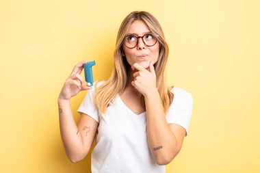 Güzel sarışın kız düşünüyor, kuşkulu ve şaşkın hissediyor. astım spreyi kavramı