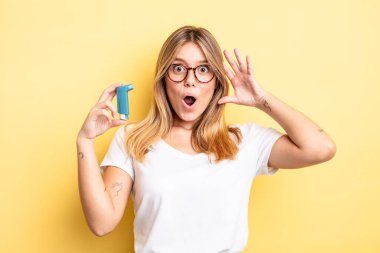 Güzel sarışın kız ellerini havaya kaldırarak çığlık atıyor. astım spreyi kavramı