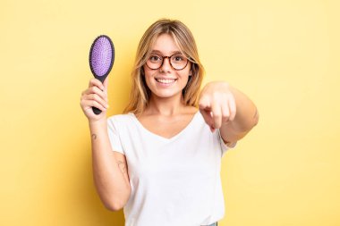 Güzel sarışın kız seni seçen kamerayı işaret ediyor. saç fırçası konsepti