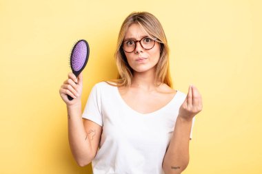 Güzel sarışın kız kapiş ya da para hareketi yapıyor, sana ödemeni söylüyor. saç fırçası konsepti