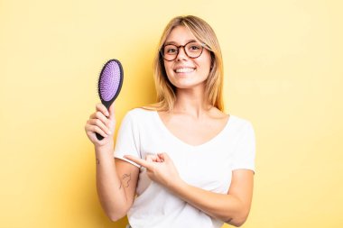 Güzel sarışın kız heyecanlı ve şaşırmış görünüyor. saç fırçası konsepti