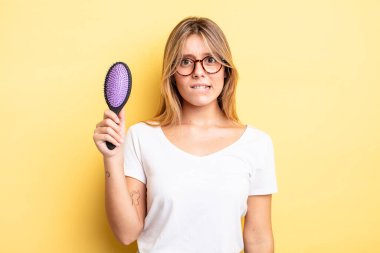 Güzel sarışın kız şaşkın ve şaşkın görünüyor. saç fırçası konsepti