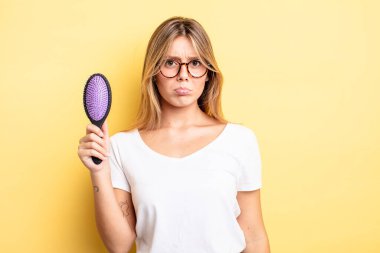 Güzel sarışın kız üzgün ve mızmızlanıyor. Mutsuz bir bakışı var ve ağlıyor. saç fırçası konsepti