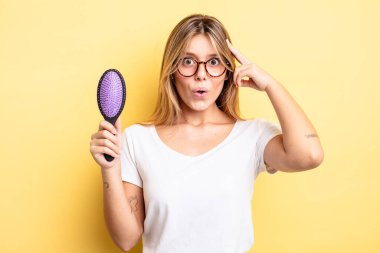 Güzel sarışın kız şaşırmış görünüyor, yeni bir düşünce, fikir ya da konsept fark ediyor. saç fırçası konsepti