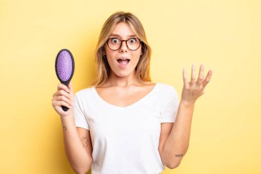 Güzel sarışın kız kendini mutlu hissediyor, bir çözüm ya da fikir bulduğuna şaşırıyor. saç fırçası konsepti