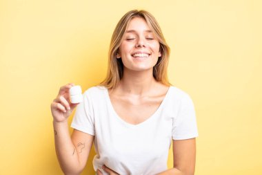 Güzel sarışın kız komik bir şakaya yüksek sesle gülüyor. hap şişesi konsepti