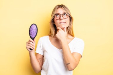 Güzel sarışın kız düşünüyor, kuşkulu ve şaşkın hissediyor. saç fırçası konsepti