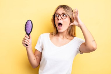 Güzel sarışın kız mutlu, heyecanlı ve şaşırmış hissediyor. saç fırçası konsepti