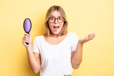 Güzel sarışın kız şok olmuş ve şaşırmış hissediyor. saç fırçası konsepti