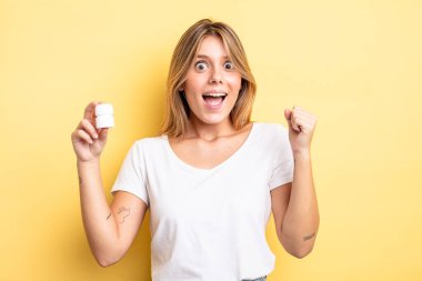 Güzel sarışın kız şokta, gülüyor ve başarıyı kutluyor. hap şişesi konsepti