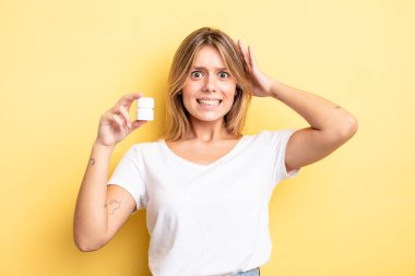 Güzel sarışın kız stresli, endişeli ya da korkmuş, elleri başının üstünde. hap şişesi konsepti