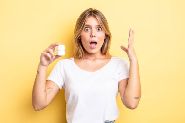 Güzel sarışın kız kendini mutlu hissediyor ve inanılmaz bir şeye hayret ediyor. hap şişesi konsepti