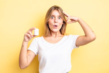 Güzel sarışın kız mutlu, şaşkın ve şaşırmış görünüyor. hap şişesi konsepti